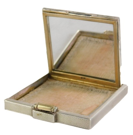 A George VI silver compact, of engine turned plain decoration, with silver gilt scroll clasp, with mesh interior and mirrored panel, maker FOS, London 1937, 3.49oz.