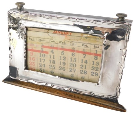 A George III desk calendar, in a stained pine ebonised frame, with a fluted silver front, and glass panel, Birmingham 1925, 12cm high, 20cm wide. (AF)