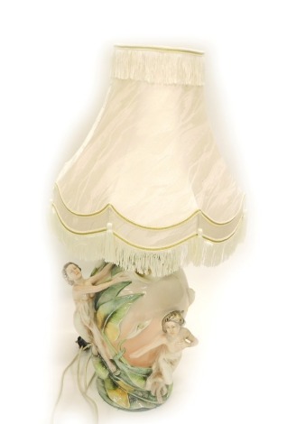 An Italian porcelain table lamp, with raised relief semi-clad females, around lilies on a pink ground, stamped made in Italy with cream shade, 84cm high.