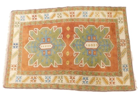 A Turkish rug, on a cream, orange and green ground, with medallions, woven with tassel ends, 196cm x 132cm.