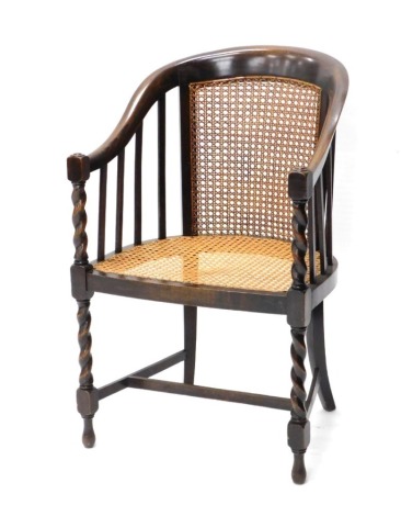 A 20thC oak bergere chair, with caned seat, on barley twist columns, with arms.