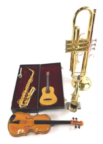 An Odyssey brass trumpet, two miniature saxophones, and a violin.