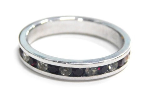 An eternity ring, tension set with red and white paste stones, in a silver coloured band, unmarked, ring size J½.