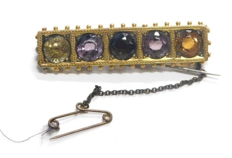 A Victorian bar brooch, set with five semi precious stones, to include garnet, topaz, citrine, smoky quartz and amethyst, with a ball design outer border, on single pin back, yellow metal stamped 15ct, 4.5cm wide, with plated safety chain, 8.3g all in.