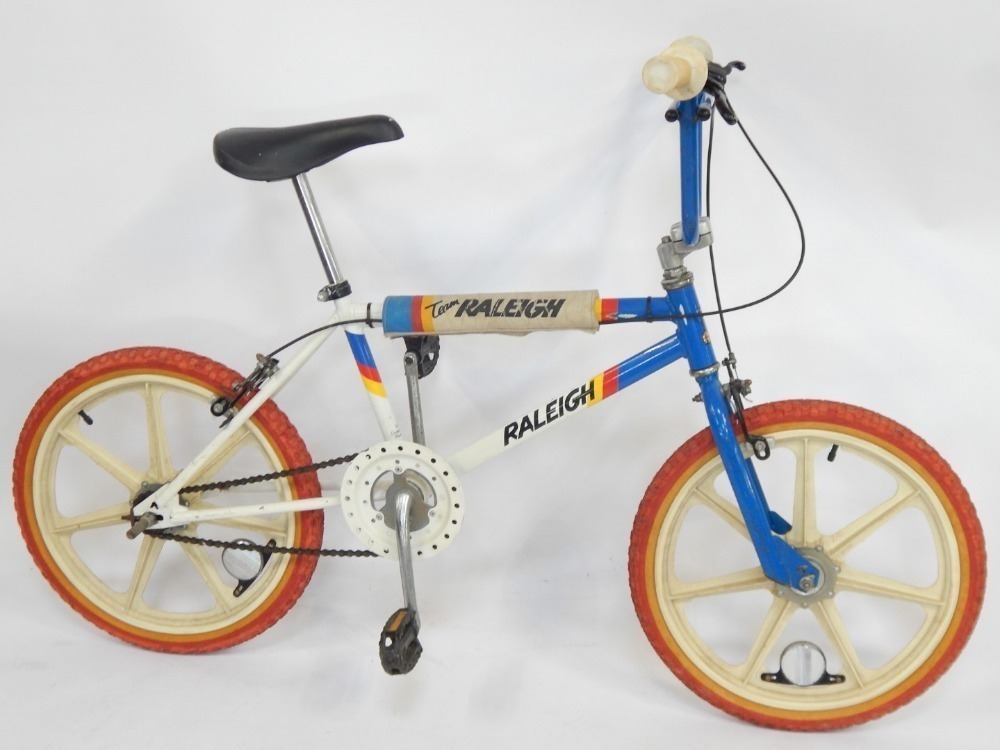 A Raleigh BMX bike with blue and white striped frame and red wheels