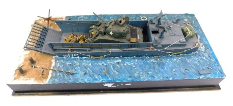 A part scratch built model of a US World War Two landing craft, with a Sherman tank, soldiers and other figures, on naturalistic shoreline base, 61cm wide.