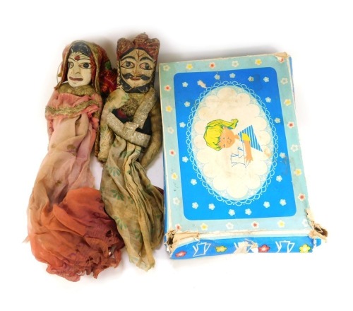 A mid century child's porcelain miniature tea service, decorated with blue flowers against a white ground, together with two Indian dolls, each with a carved wooden face and cloth bodies.