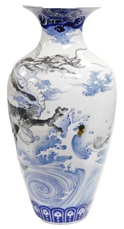 A large Meiji period Japanese Arita ovoid vase, with everted rim, decorated with a dragon in monochrome tones, within blue clouds and waves below, lappet border, 77cm high. (AF)