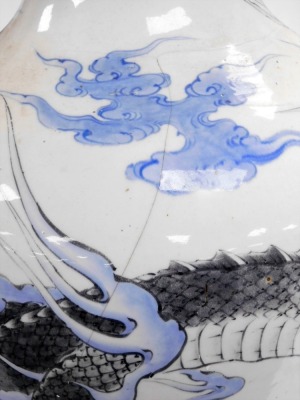 A large Meiji period Japanese Arita ovoid vase, with everted rim, decorated with a dragon in monochrome tones, within blue clouds and waves below, lappet border, 77cm high. (AF) - 7