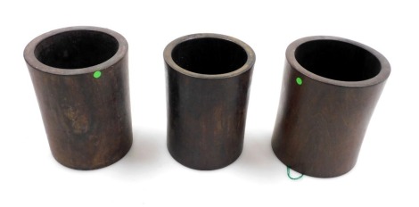 Three Chinese hardwood cylindrical brush pots, of plain design, one with a hole to the base, the tallest 14.5cm high.