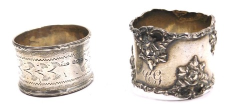 An Edward VII silver napkin ring, with embossed floral decoration, monogram engraved, import marks, Birmingham 1904, and a further napkin ring with engraved decoration, circular reserve, monogram engraved, Birmingham 1910, 2.08oz.