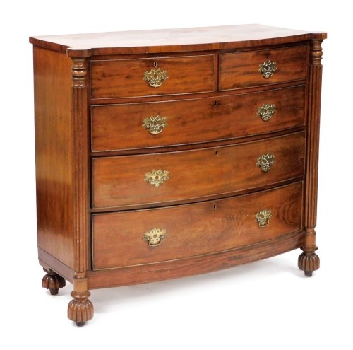 A late Georgian mahogany bow front chest, of two short over three long graduated drawers, raised on turned and fluted columns, over fluted circular feet, 115cm high, 130cm wide, 54.5cm deep.