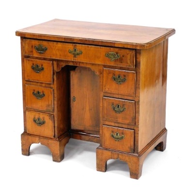 An early 18thC Georgian walnut kneehole desk, with one long over six small drawers, and recess with central door, raised on bracket feet, 78.5cm high, 82cm wide, 49cm deep.