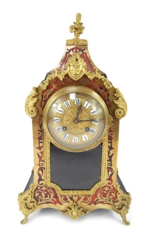 A 19thC French Boulle mantel clock, the circular embossed brass face with raised white enamel Roman numerals, eight day movement, the case of shaped form with floral finial, ormolu mounts depicting a face, various flowers, scrolls, etc., with key and pend