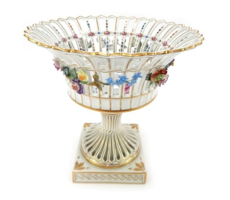 A 20thC Dresden porcelain pedestal fruit bowl, the pierced bowl decorated with painted and applied flowers, on a square base, gilt heightened, printed marks, 25cm high.