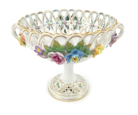 A 20thC Dresden porcelain two handled pedestal dish, the pierced bowl decorated with painted and applied flowers, on a circular foot, gilt heightened, printed marks, 18cm high.