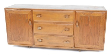 An Ercol elm sideboard, the rectangular top with a moulded edge, above three drawers flanked by two cupboards, on castors, 67cm high, 155cm wide, 43cm deep.