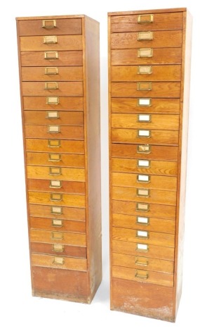 A pair of early 20thC oak filing cabinets, each with eighteen drawers, with plated brass handles, 200cm high, 48cm wide, 35cm deep.