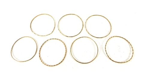 Seven yellow metal bangles, three of hammered design and four of twist design, unmarked believed to be 9ct gold, 30.1g.