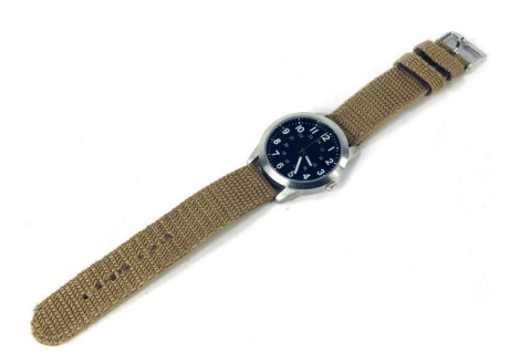 An Eagle Press gentleman's field watch, with stainless steel watch head, black enamel dial with white numerals, on canvas strap, the dial 3.5cm diameter.