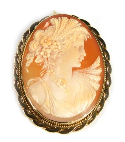 A 9ct gold framed shell cameo brooch, the cameo depicting maiden in flowing dress, with a double beaded and petalated border on single pin back with safety chain, 5cm x 4cm, 16.5g all in.