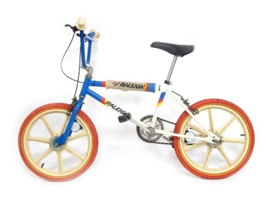 A Raleigh BMX bike, with blue and white striped frame and red wheels.