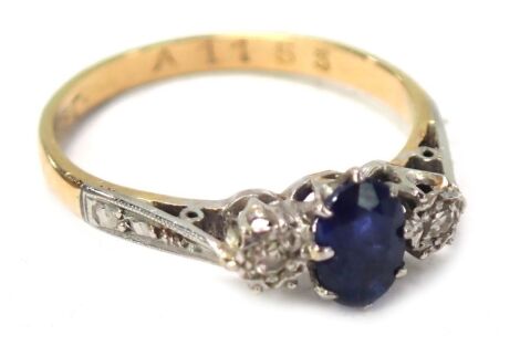 An 18ct gold sapphire and diamond dress ring, the central oval sapphire in claw setting, flanked by two tiny illusion set diamonds, on platinum splayed shoulders in platinum setting, on a yellow metal band, ring size L½, 2.1g.