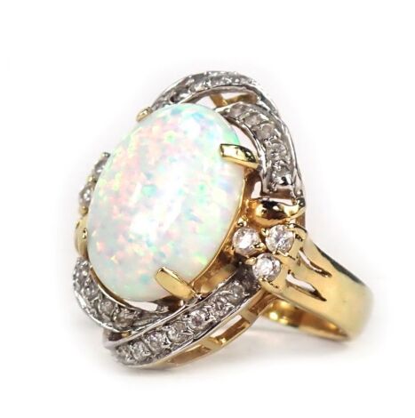 A dress ring, with oval imitation opal, in four claw setting, surrounded by swirl of diamonds, in yellow metal frame stamped 585, ring size N½, 5.8g all in.