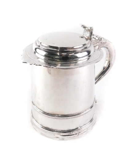 A Queen Anne silver lidded tankard, the hinged lid, shell cast thumb piece, the scroll handle with tapering beads, the cylindrical body with moulded bands, engraved to underside Queen Anne 1703, London 1703, possibly by Robert Peake, 32.94oz, 18cm high.