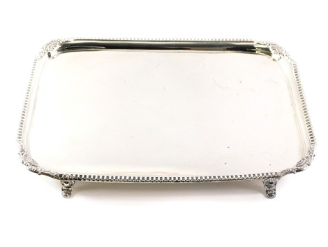 A George III silver rectangular tray, with a gadrooned border and leaf cast corners on tapering feet, headed by shells, Sheffield 1808, maker stamped T.L, 64.81oz, 47cm x 33.5cm.