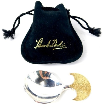 An Elizabeth II silver caddy spoon by Stuart Devlin, with a silver gilt and brushed handle, 7.5cm high, stamped SD London 1984, with pouch, 1.01oz.