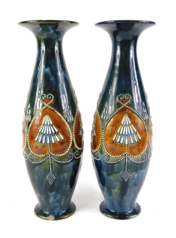 A near pair of Royal Doulton stoneware vases, each with a flared rim, the body with raised bead work decoration in stylised hearts, on a domed foot, impressed marks to underside and decorators initials limited edition PB and MH, possibly Marion Holbrook, 