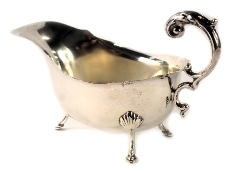 A George V silver sauce boat, with fluted border and camphor leaf handle, on shell tripod feet, Birmingham 1925, 2.29oz.