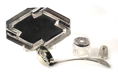 A George V silver ashtray, with engine turned border, Birmingham, 1.78oz, a silver topped and cut glass dressing table jar, silver plated ladle, and silver plated thimble. (4)