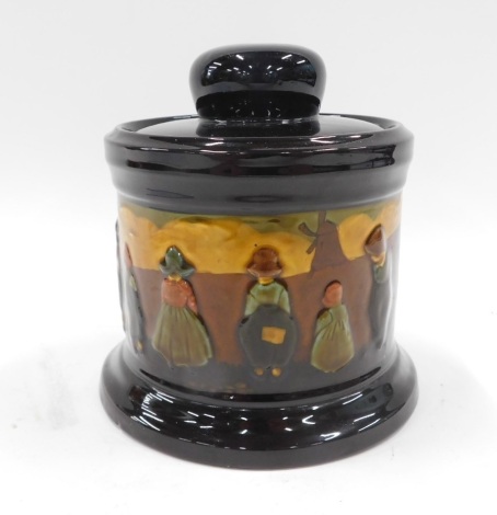 A Royal Doulton tobacco jar, with brown a black treacle glazed decoration depicting figures and windmills, lid associated, 18cm high.