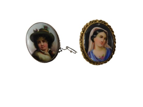 Two porcelain brooches, comprising a circular portrait brooch of child in green cap, in a white metal border with rope twist sides, single pin back with safety chain, 4.5cm x 3.5cm, and a plated portrait of a lady, 4.5cm x 3.5cm. (2)