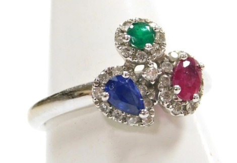 A ruby sapphire and emerald ring, set with a brilliant cut emerald, oval cut ruby, and pear shaped sapphire, each in a surround of diamonds, set in white metal, stamped 18k, size L, 4.4g.