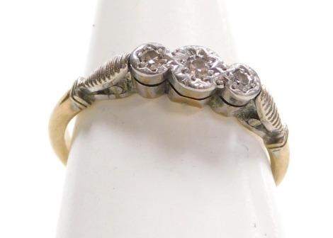 A diamond three stone ring, in an illusion setting, in white and yellow metal, stamped 9ct and plat, size M, 2.3g.