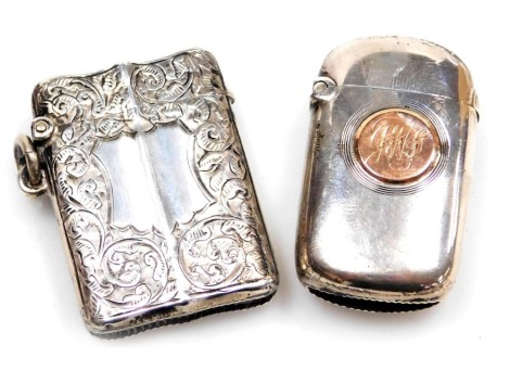 A Victorian silver Vesta case, of oblong form, with a gilt circular reserve, monogram engraved, London 1899, and an Edward VII silver serpentine shaped Vesta case, with engraved foliate decoration, vacant central shield reserve, Birmingham 1903. (2)