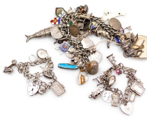 A silver curb link charm bracelet, with approximately fifty-four charms as fitted, on a heart shaped padlock clasp, a further silver charm bracelet with eleven charms as fitted on a heart shaped padlock clasp with safety chain, and a silver charm bracelet