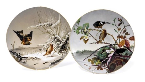 A pair of late 19thC pottery chargers, outside decorated with birds in a winter landscape, and birds with a nest amongst wild roses, 37cm wide.