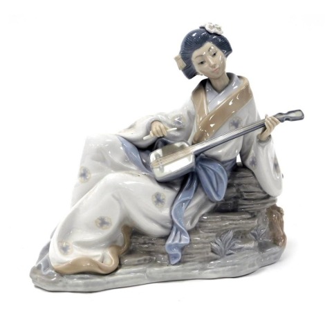 A Nao porcelain figure of a geisha girl, model seated playing a Shamisen lute, printed marks, 29cm wide.