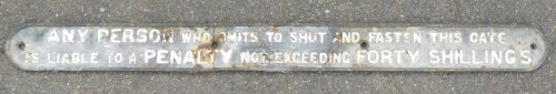 An early 20thC black and white painted cast iron railway warning sign, "Any Person Who Omits to Shut and Fasten This Gate Is Liable To A Penalty Not Exceeding Forty Shillings", in two sections, 103cm wide.