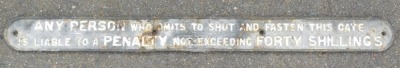 An early 20thC black and white painted cast iron railway warning sign, "Any Person Who Omits to Shut and Fasten This Gate Is Liable To A Penalty Not Exceeding Forty Shillings", in two sections, 103cm wide.