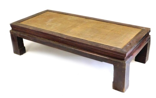 A Chinese hardwood rectangular occasional table, with a rattan top, raised on square block feet, 47cm high, 179cm wide, 85cm deep.