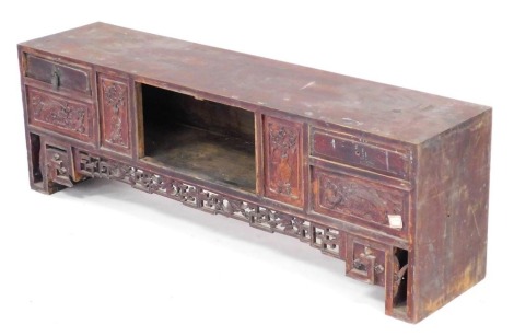 A stained elm table top cabinet, with an open section flanked by six drawers, some with carved decoration, above a carved frieze, raised on carved square legs, 34cm high, 103cm wide, 24cm deep.