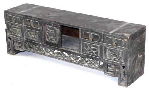 A Chinese stained hardwood table cabinet, with a pair of central doors, one lacking, flanked by four short over four further drawers, with floral carved detailing, above a floral carved frieze and floral carved square legs, 35cm high, 105cm wide, 25cm dee