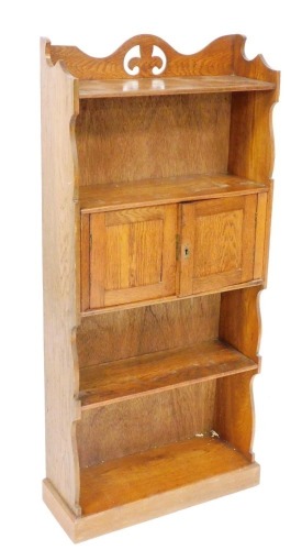 A Victorian oak open bookcase, with a carved and galleried back, over a single shelf over a pair of cupboard doors, with a further shelf below, raised on a plinth base, 120cm high, 53.5cm wide, 19cm deep.