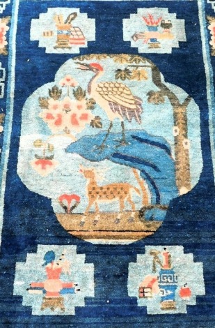 A Chinese blue ground rug, decorated with a central medallion with a crane, Buddhist emblems within geometric borders, 158cm x 95cm.