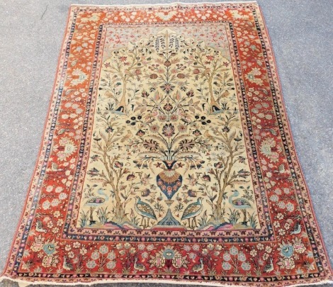 A Kashan cream ground tree of life rug, the mihrab decorated internally with a vase of flowers, trees with birds, further birds, etc., within repeating bird and floral borders, 200cm x 128cm.